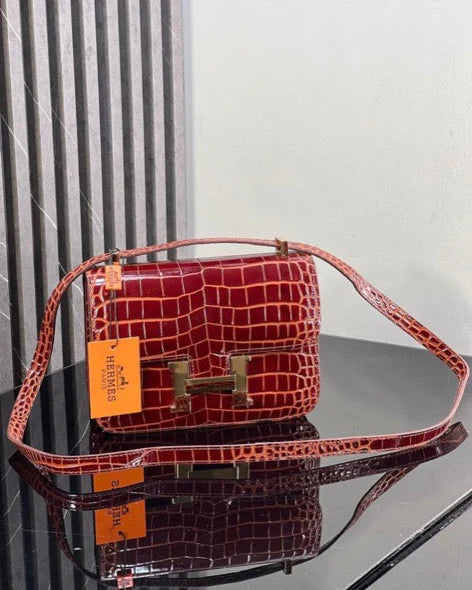 Red handbag with gold accents on a reflective surface