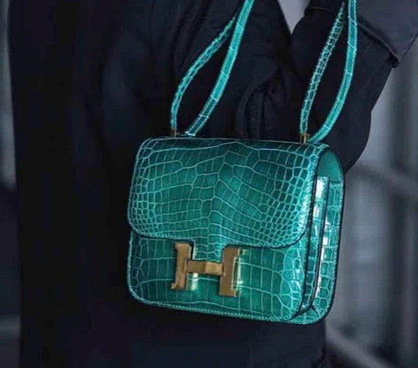 Teal handbag with gold hardware on a dark background
