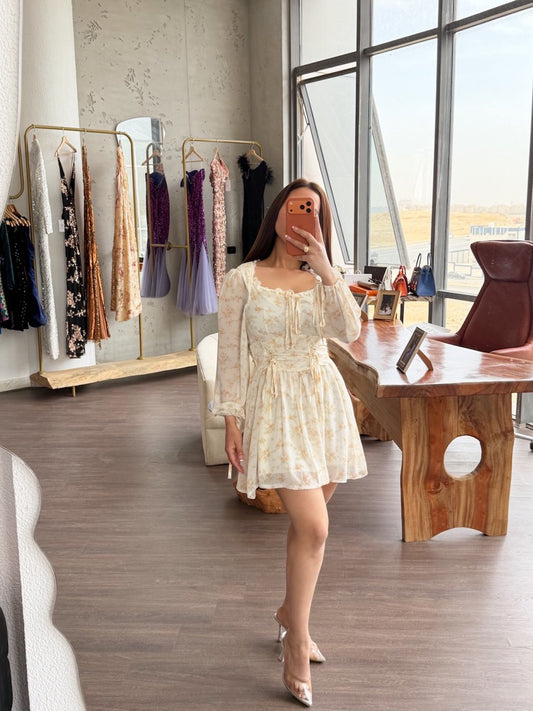 Woman taking a mirror selfie in a stylish room with clothing racks and a large window.