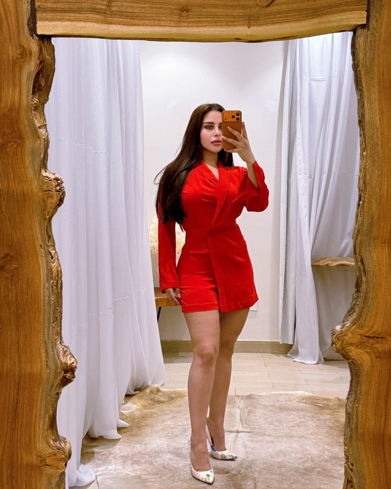 Person wearing a red outfit taking a mirror selfie in a room with white curtains.