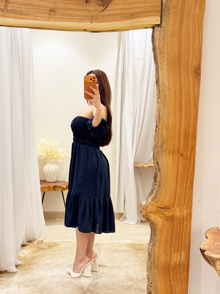 Woman taking a mirror selfie wearing a navy blue dress in a room with wooden decor.