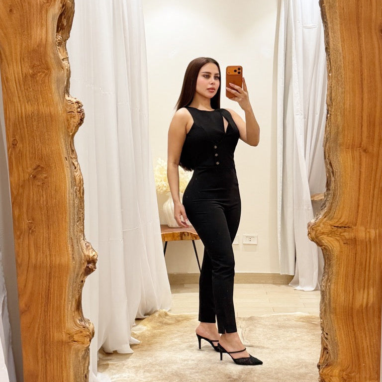 Woman taking a mirror selfie wearing a black outfit in a room with white curtains.