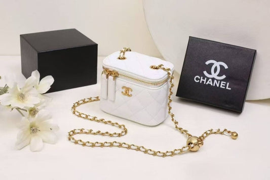 White Chanel handbag with gold chain and packaging on a white background