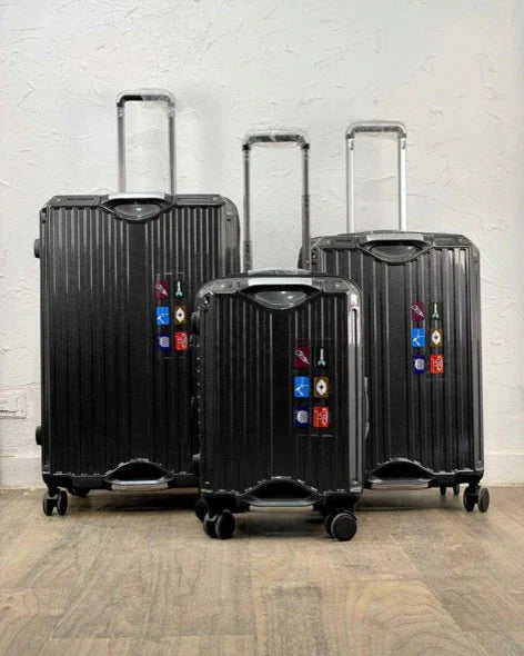 Set of black suitcases with colorful tags on a wooden floor.